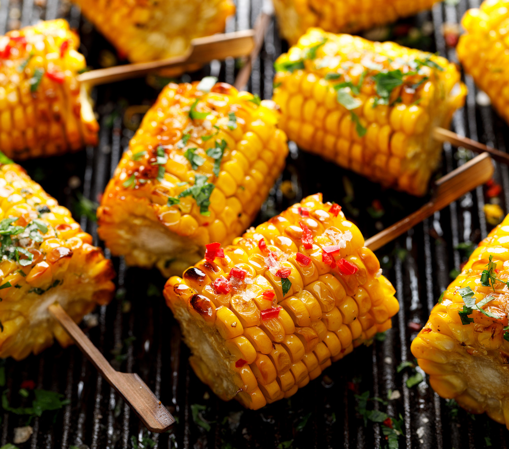 Köstlich: Maislollies grillen und mit Chimichurri sowie Knoblauch-Butter mit Paprika und Chili bestreichen.