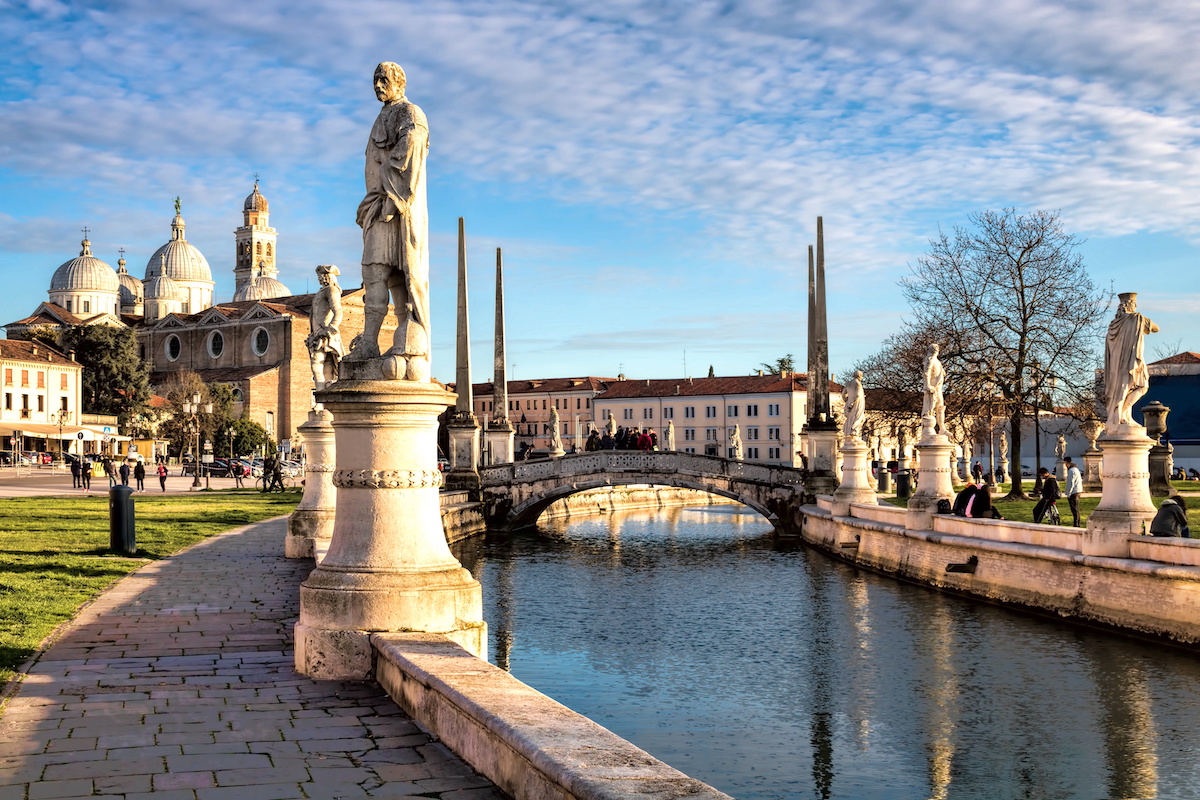 Zentrum des Prato della Valle ist eine Insel, die von einem Wasserkanal mit vier Brücken und 78 Statuen umrundet wird; im Hintergrund die Basilica di Santa Giustina.